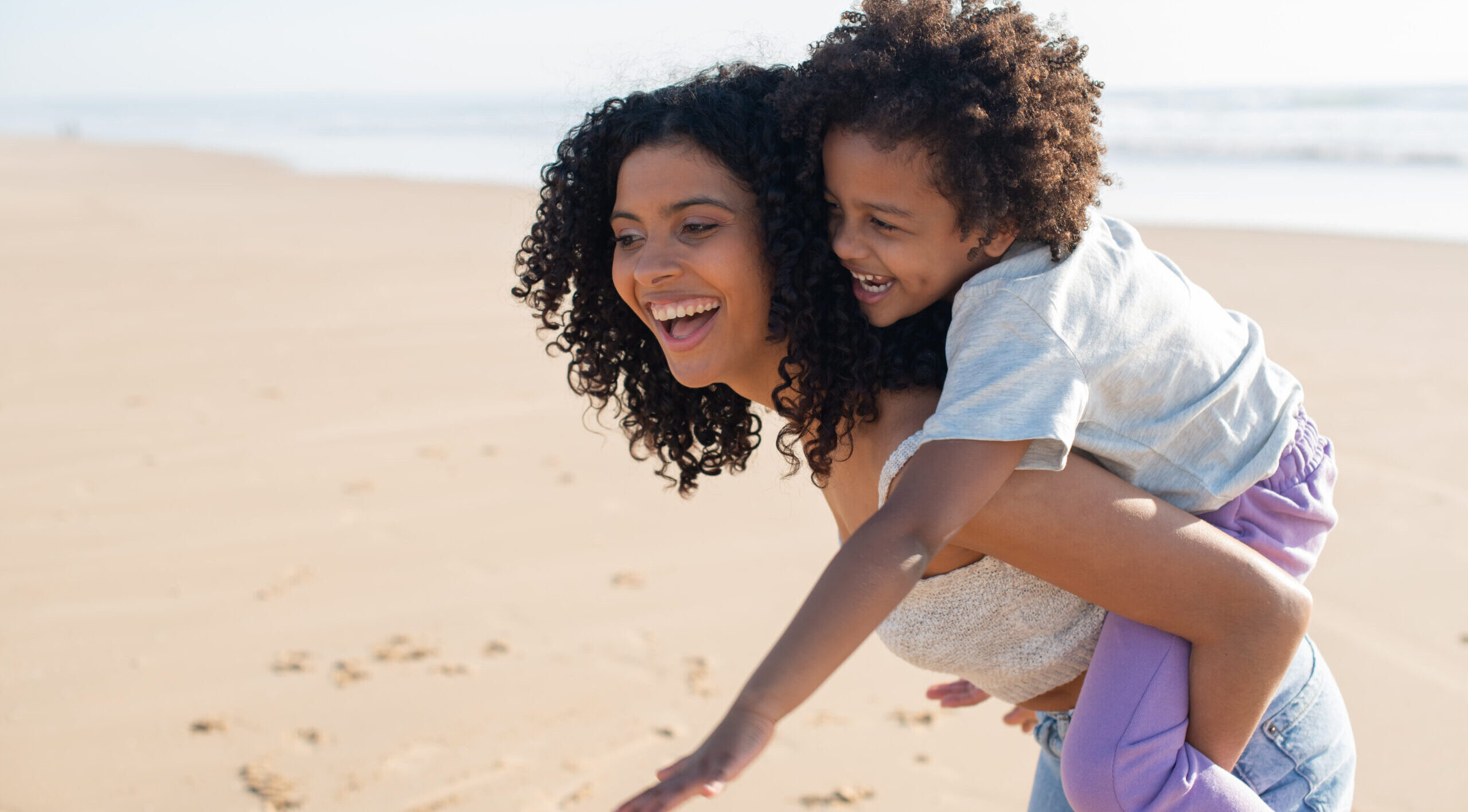 African American mother and child laughing, playing, riding on back. Family Time - Buying Luxury Real Estate Bahamas