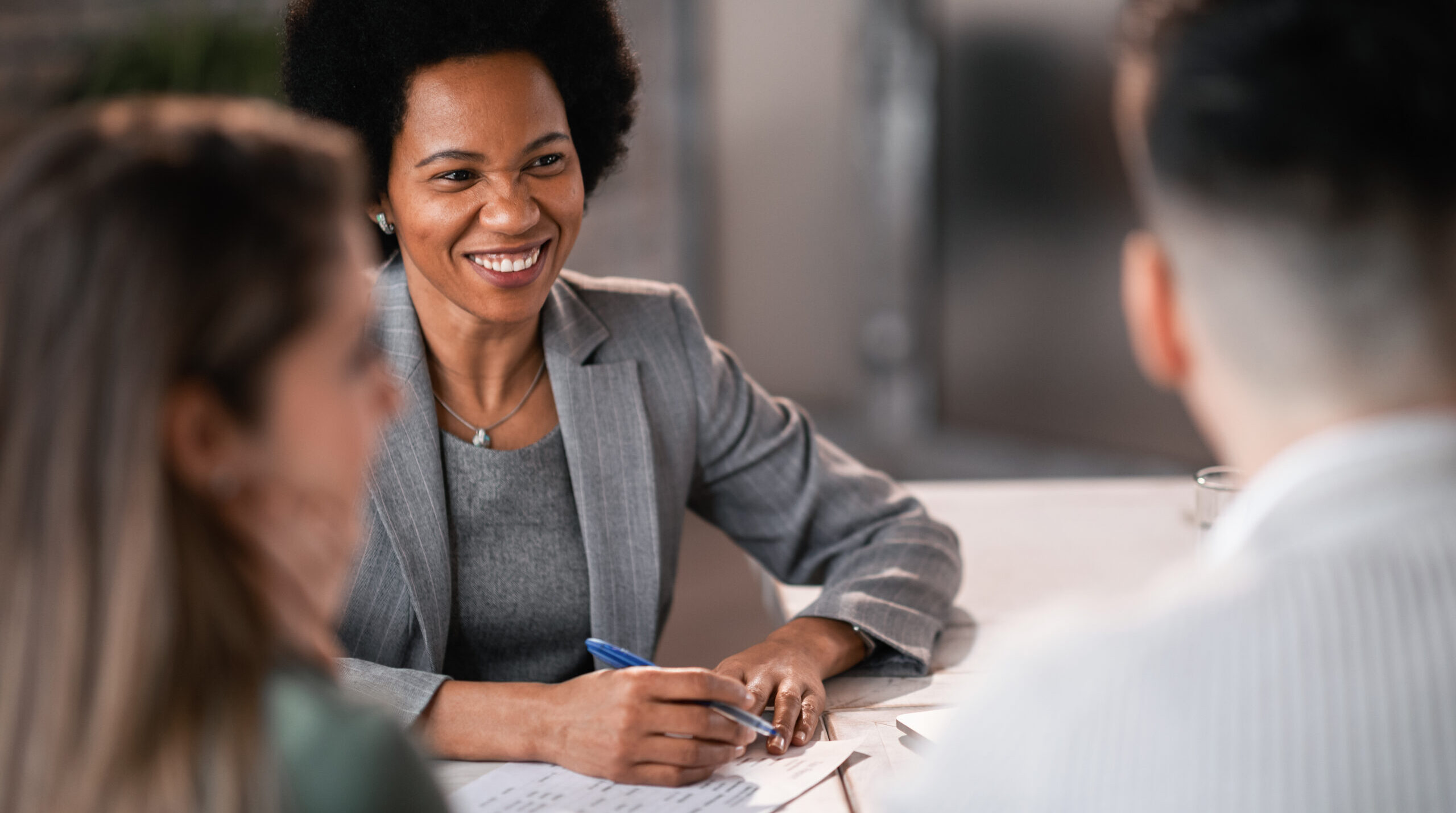 Happy African American legal advisor giving consultations to a couple while making their future real estate investment plans